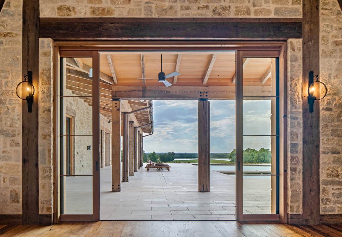 Interior view looking through the glass pocket doors to the patio at Texas Ranch, a custom home designed and built by Farmer Payne Architects.
