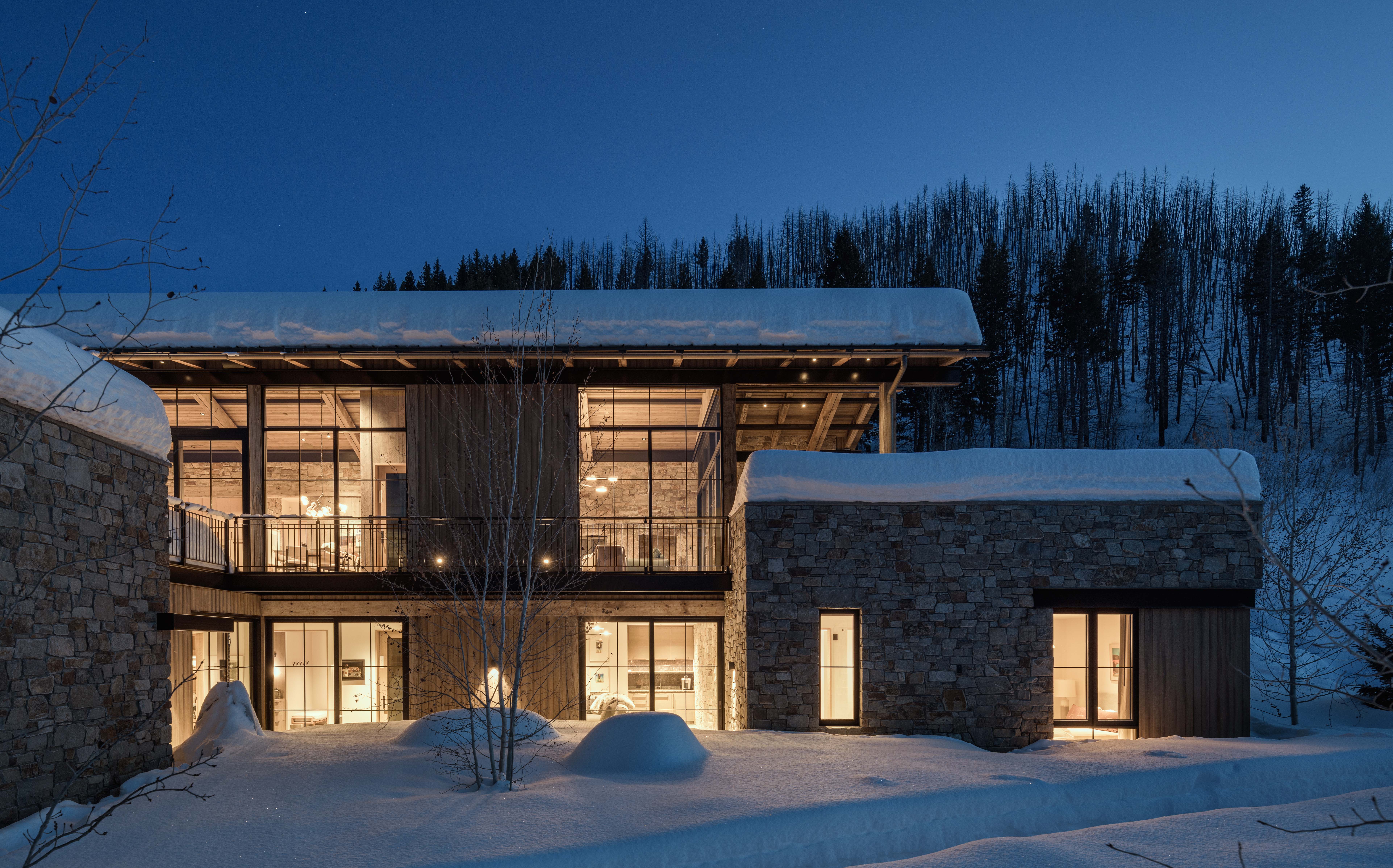 contemporary mountain home exterior, featuring rock walls and a grated bridge connecting two terraces