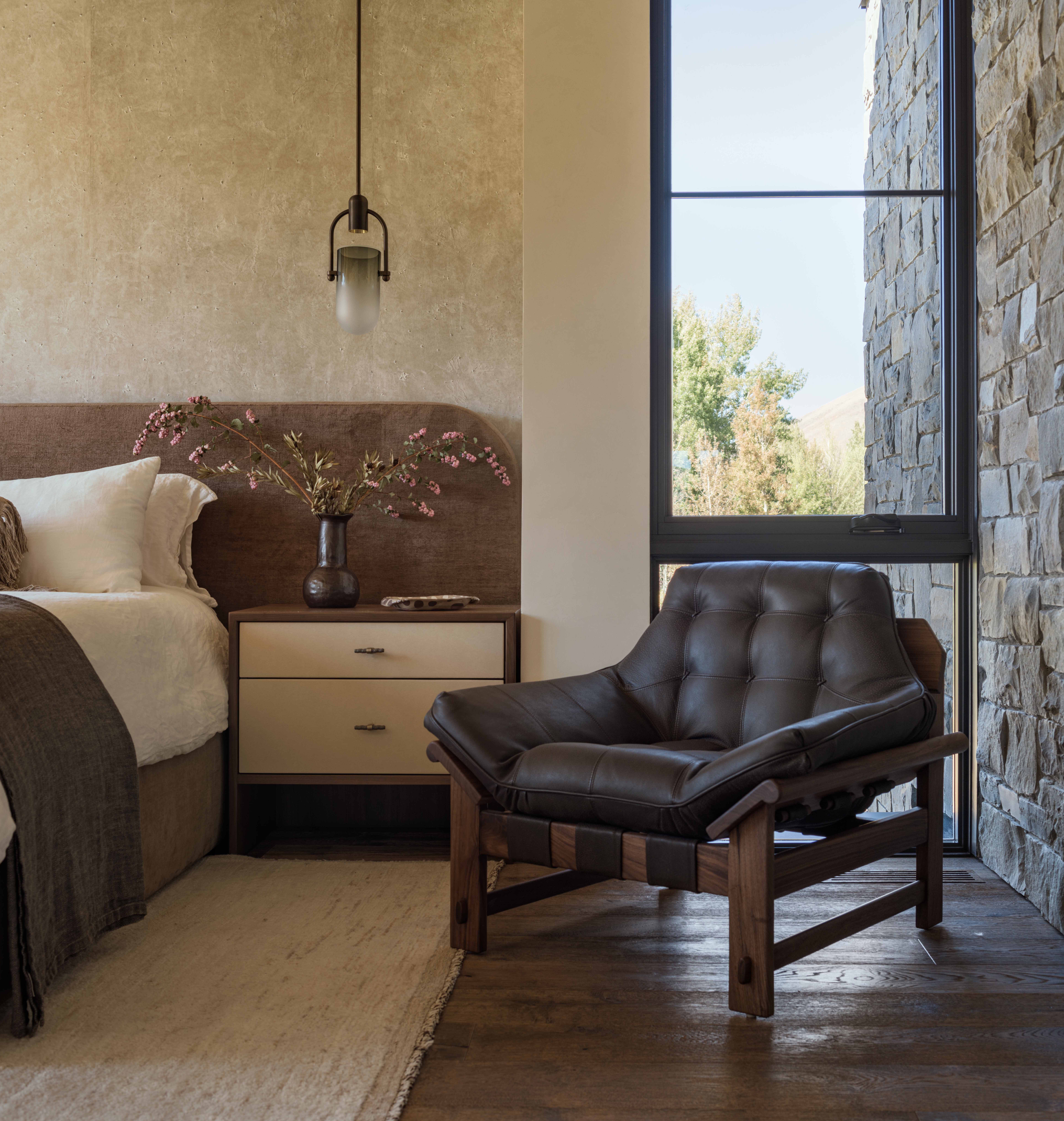 contemporary mountain home master bedroom, plaster accent wall, featuring a stone wall that continues outside